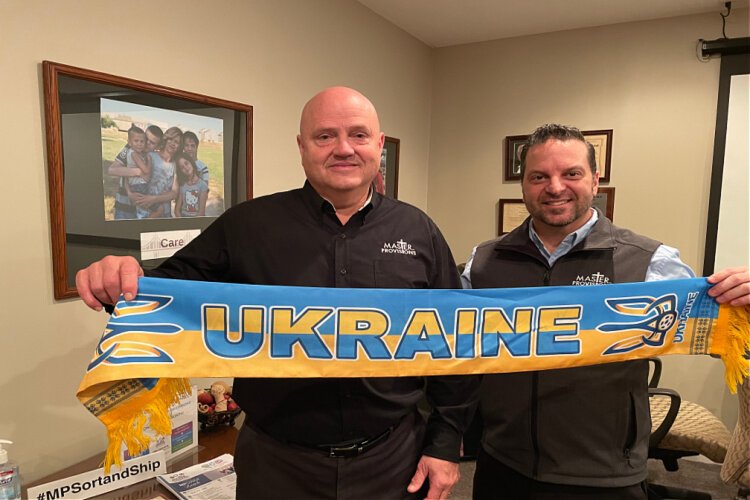 Master Provisions founder Roger Babik, left, and Travis Nipper, communications director, with a banner from Ukraine, the first country assisted by the not-for-profit.